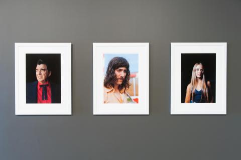 An installation view of three colour photographs — portraits of people — installed in a gallery space