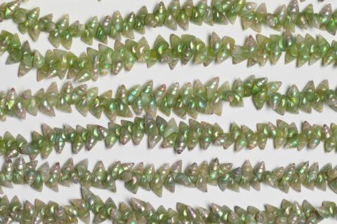 A detail view of strands of necklace made from green maireener shells