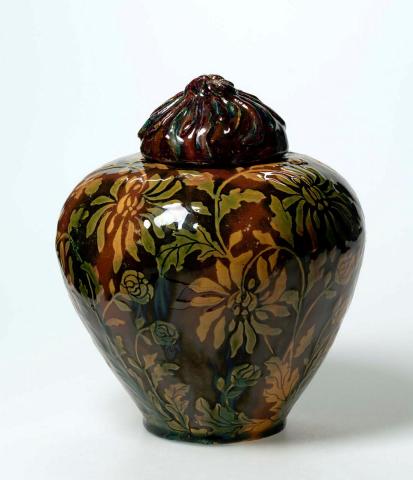 Artwork Covered jar this artwork made of Earthenware, hand-built, dipped gold clay, scraffito design of chrysanthemums, double glazed and with moulded floral cover, created in 1933-01-01