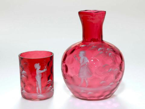 Artwork Water carafe and tumbler this artwork made of Ruby glass with dimpled interior and square lip.  Spherical body enamelled in white with the figure of a girl in a landscape.  The tumbler decorated with the figure of a boy, created in 1890-01-01