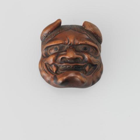Artwork Netsuke:  (two-sided:  mask of a demon and mask of Okame, Goddess of Mirth) this artwork made of Carved boxwood, created in 1850-01-01