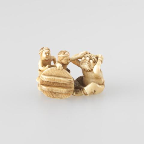 Artwork Netsuke:  (two figures with diadems (crowns) seated in a bath tub and teasing a demon) this artwork made of Carved ivory, created in 1850-01-01