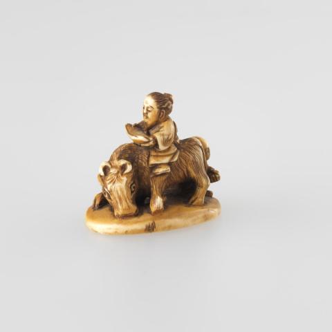 Artwork Netsuke:  (Lao-tzu riding a buffalo) this artwork made of Carved ivory with flat base.  Bamboo leaves engraved beneath base, created in 1800-01-01