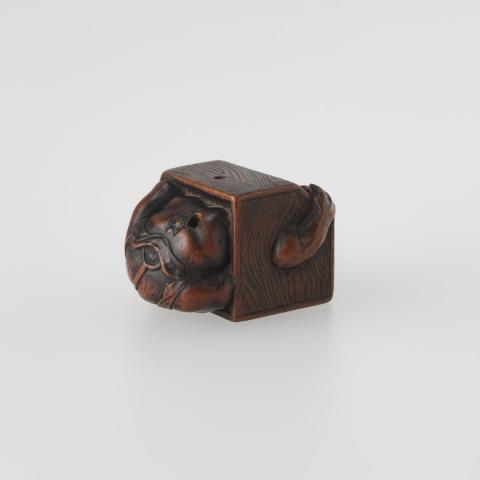 Artwork Netsuke:  (man disappearing into a charcoal warmer) this artwork made of Carved boxwood, created in 1800-01-01