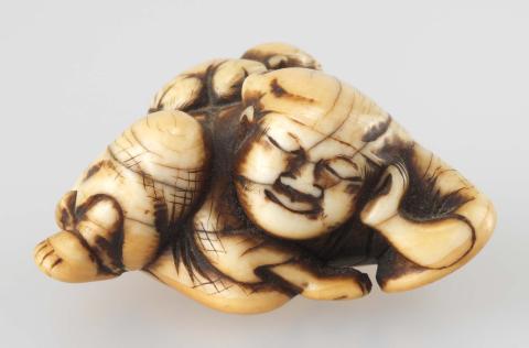 Artwork Netsuke:  (reclining man with a monkey on his back) this artwork made of Carved ivory, created in 1800-01-01