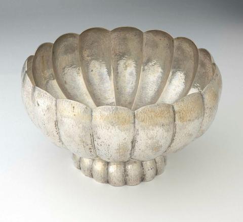 Artwork Footed bowl this artwork made of Silver, squat spherical bowl with sixteen ridges spreading from a central base and terminating in a scalloped edge.  Set on a similarly formed base.  Hammered finish, created in 1940-01-01