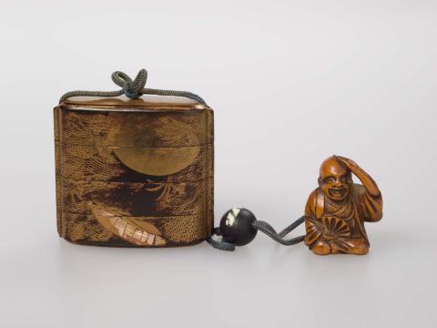 Artwork Inro with netsuke:  (insect and foliage) this artwork made of Wood in three compartments with black lacquer, gold leaf and mother of pearl inlay.  Black glass toggle with boxwood netsuke of a monk with fan and blue cord, created in 1800-01-01