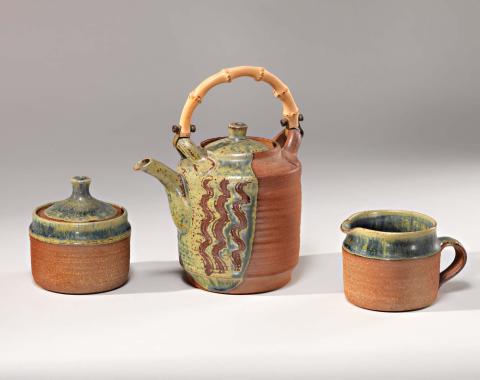 Artwork Tea-set (teapot, sugar bowl and milk jug) this artwork made of Stoneware, thrown cylindrical brown body with partial blue green glaze and combed zig-zag decoration on the teapot. Cane handle, created in 1958-01-01