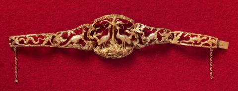 Artwork Bracelet this artwork made of Gold modelled in high relief with rusticated frames. The central section with an emu and brolga separated by a palm tree and subsidiary links depicting snake, kangaroo, possum and lizard
