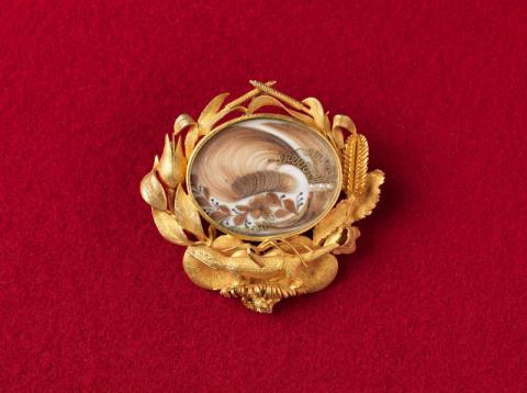 Artwork Archer mourning brooch this artwork made of Matt gold with oval section (containing hair), embroidered over silk with seed pearls, chain and pin, created in 1855-01-01