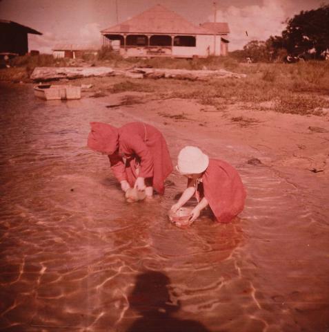 Artwork (Two small girls in red, filling sand buckets in shallow water) this artwork made of Type C photograph on paper, created in 1935-01-01