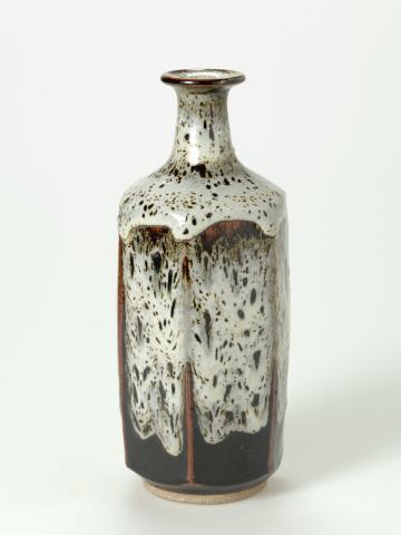 Artwork Facetted bottle this artwork made of Stoneware, thrown and wire cut with six facets and matt white Shino type glaze over Tenmoku glaze, created in 1970-01-01