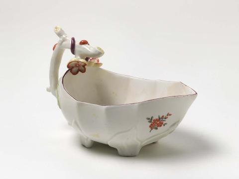 Artwork Sauce boat this artwork made of Soft-paste porcelain, moulded with bows and flowers, overglaze floral sprigs highlighted in purple, green, yellow, red and blue, rimmed in brown