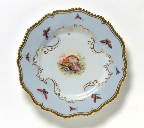 Artwork Plate:  (shell motif) this artwork made of Soft-paste porcelain, six-lobed gadrooned edge and pale blue border with painted central cartouche in polychrome overglaze colours.  Gilt details, created in 1813-01-01