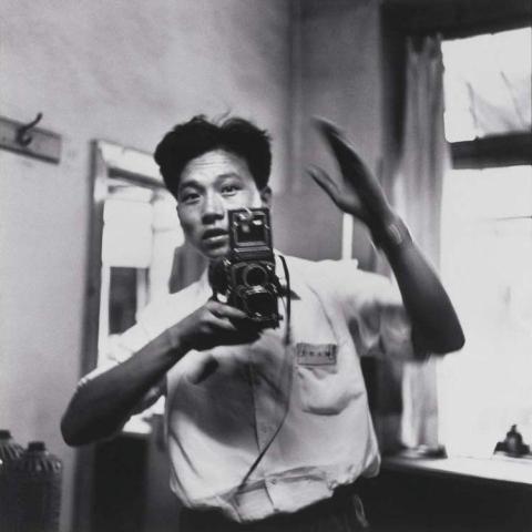 A black-and-white photograph of a person with short dark hair taking a photo of themself in 1967.