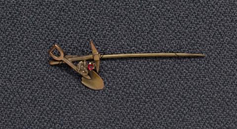 Artwork Goldfields stick-pin (crossed pick and shovel with garnet) this artwork made of Gold, gold nugget and garnet