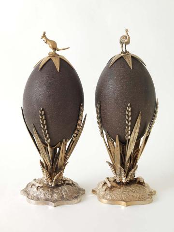 Artwork Pair of silver-mounted emu eggs this artwork made of Emu eggs, supported on ears of wheat with lizards and frogs on domed base and kangaroo and emu finials in silver, each with a glass dome and ebonised circular stand, created in 1879-01-01