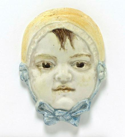 Artwork Plaque: Baby girl in bonnet and bow this artwork made of Earthenware, white clay modelled with details in brown, yellow and blue, created in 1936-01-01