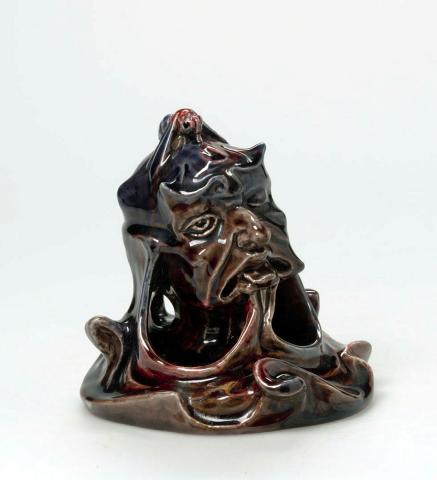 Artwork Figurine: When you're on a good thing stick to it this artwork made of Earthenware, modelled in the form of a devil on a scrolling watery base, with a hornet on its head, glazed mulberry and red, created in 1920-01-01