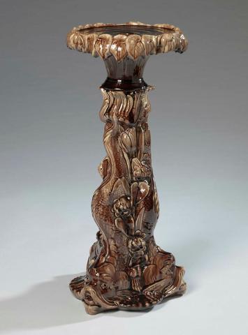 Artwork Pedestal this artwork made of Earthenware, modelled with the form of three dolphins with tails entwining and glazed light and dark brown, created in 1895-01-01