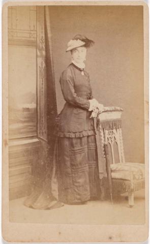 Artwork (Lady with hat and umbrella standing beside chair) this artwork made of Albumen photograph on paper mounted on card, created in 1872-01-01