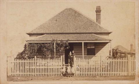 Artwork (Woman, baby and three children in front of Brisbane shingle-roofed house) this artwork made of Albumen photograph on paper mounted on card