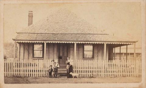 Artwork (Woman, baby, three children and dog in front of Brisbane shingle-roofed house) this artwork made of Albumen photograph on paper mounted on card