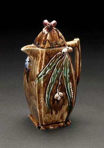 Artwork Coffeepot this artwork made of Hand-built swelling rectangular profile modelled with applied gumnuts and leaves, glazed red and green and the body glazed brown, created in 1936-01-01