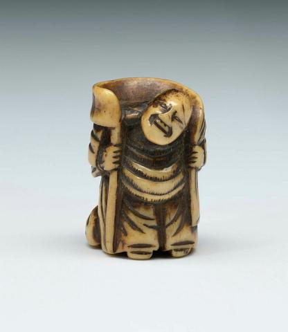 Artwork Netsuke:  (man bearing pack) this artwork made of Ivory, carved and incised, created in 1800-01-01