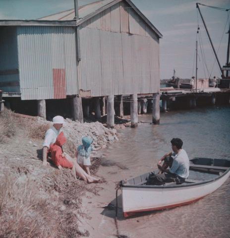 Artwork (J.H. Simmonds, Rosemary and Margaret and a man in a boat near fishing jetty and shed) this artwork made of Cellulose acetate Dufay colour transparency (originally in a glass mount), created in 1935-01-01