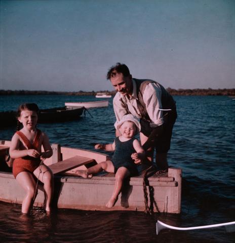 Artwork (J.H. Simmonds holding Margaret, Rosemary sitting on the edge of a boat) this artwork made of Cellulose acetate Dufay colour transparency (originally in a glass mount), created in 1935-01-01