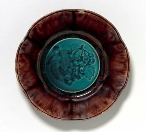 Artwork Plate this artwork made of Earthenware the well impressed with a design of grapes and glazed blue with tortoiseshell glazed rim, created in 1836-01-01