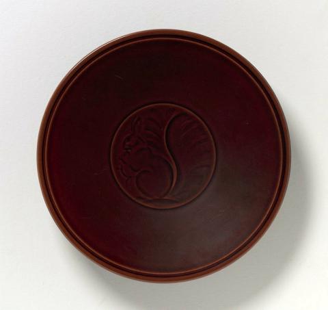 Artwork Plate this artwork made of Stoneware, interior incised with a squirrel and glazed maroon, created in 1950-01-01