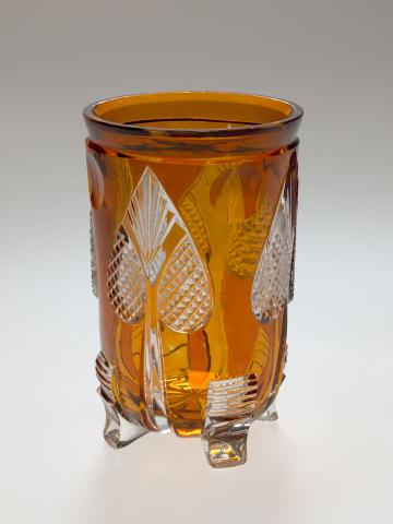 Artwork Beaker this artwork made of Clear glass stained amber and wheelcut with a design of four spade motifs. Four small feet, created in 1840-01-01