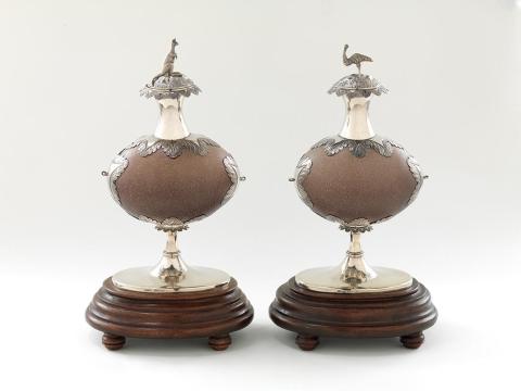 Artwork Pair of inkwells this artwork made of Emu eggs mounted in engraved silver and surmounted with the cast silver figures of an emu and a kangaroo. Turned and stained wooden bases