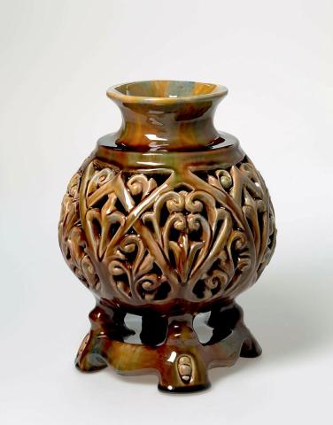 Artwork Vase this artwork made of Earthenware, hand-built double walled form on stand and pierced with a formal pattern. Glazed brown and colours, created in 1937-01-01