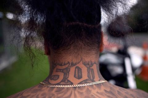 A photograph of a person from behind with the number 501 tattooed on the back of their neck, and their long hair tied up.