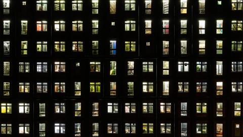 An image of many lit windows in an apartment block viewed at night; however, this view is in fact an installation miniature.