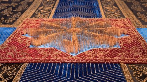 An up-close image of a detail of an embroidered artwork with 100s of pins or needles protruding to form detailed designs.