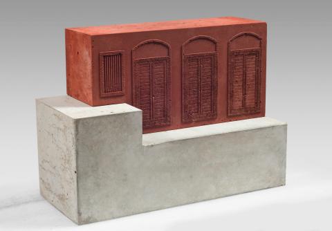 An architectural sculpture made of concrete, with a red 'wall' with engraved windows rising out of grey concrete foundations.