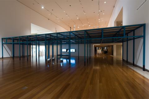 An installation view of black scaffolding forming a hut-type space in the gallery at QAG.
