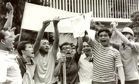 A black-and-white photograph of young men protesting.