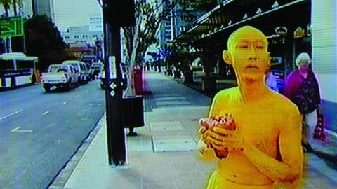 A man painted yellow, from head to toe, walks the streets of Brisbane, carrying a heart.
