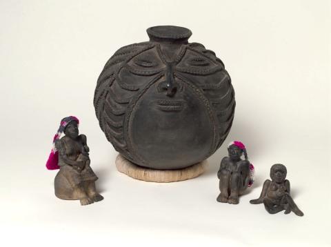 Four earthenware works, including three small figures and one large round pot with a face design applied.