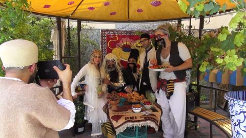 A photograph of someone taking a photograph of a group of Iranian people in fanciful costume, smiling.