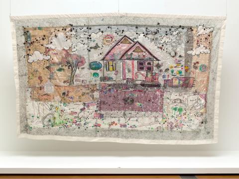 An embroidered work depicting a house and garden in soft, warm colours.