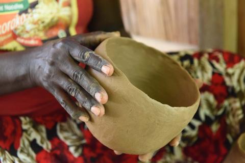 A close-up photograph of a woman's hands holding a pot that she is building.