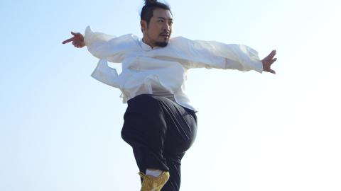 A still photograph of a man in midair, leaping; he looks away from the camera.