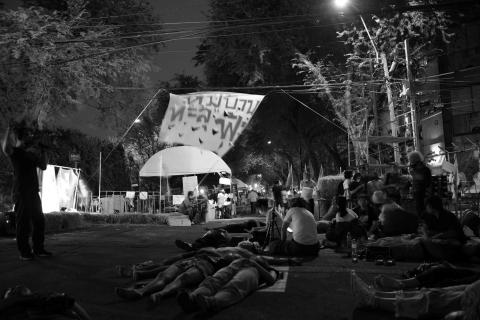 A black-and-white photo of people sitting and lying on the ground.