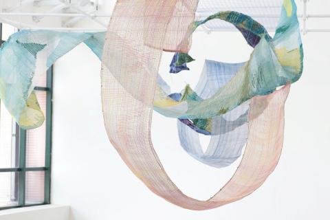 A work made of gauzy ribbons of fabric in soft blues and pinks.